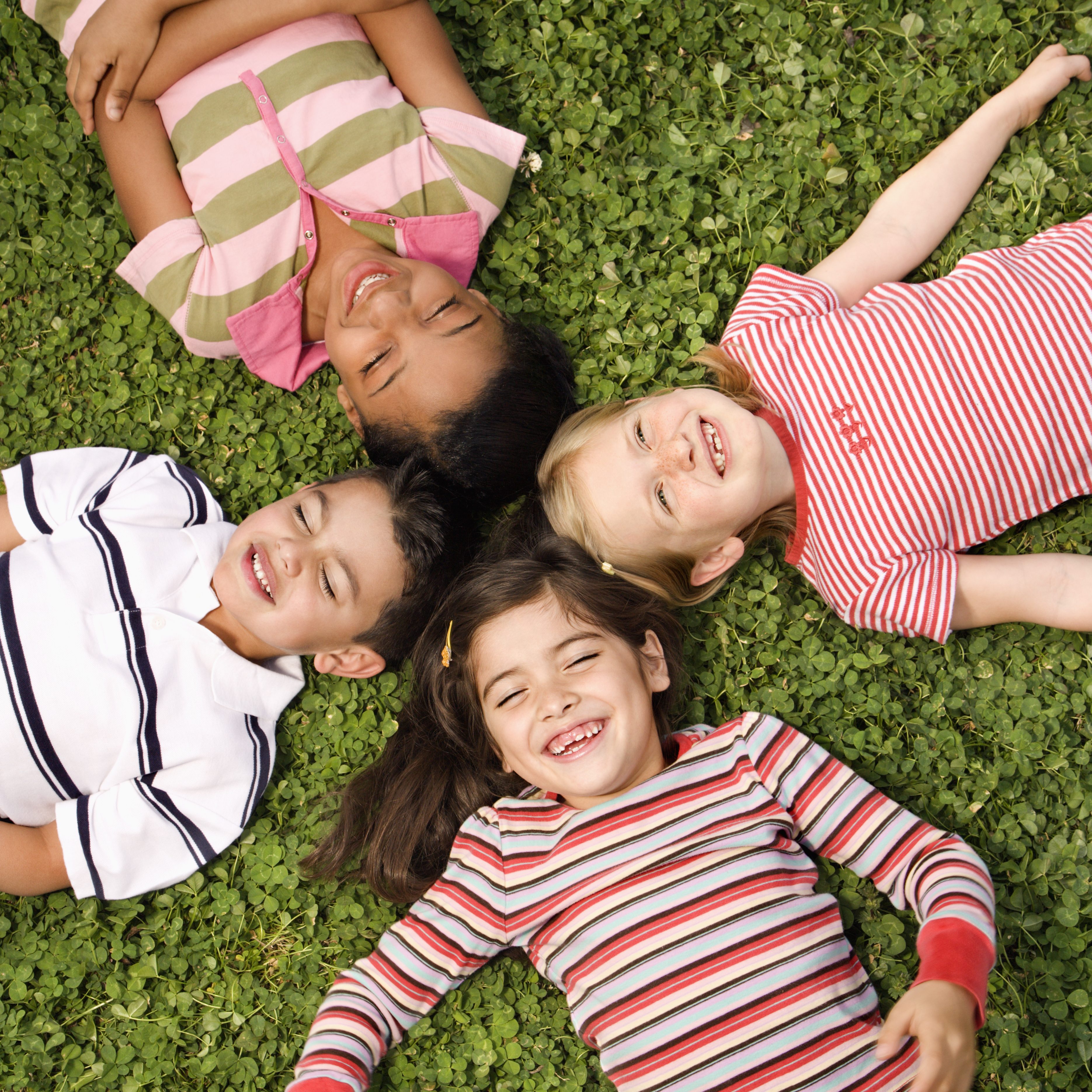 Children lying in clover with heads together. Vertically framed shot.